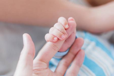 抱小宝宝婴儿抱着他的手指.小宝宝和成年妇女的手.柔情的时刻照片