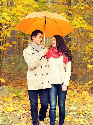 爱情关系季节家庭和人的概念微笑的情侣与伞走在秋天的公园